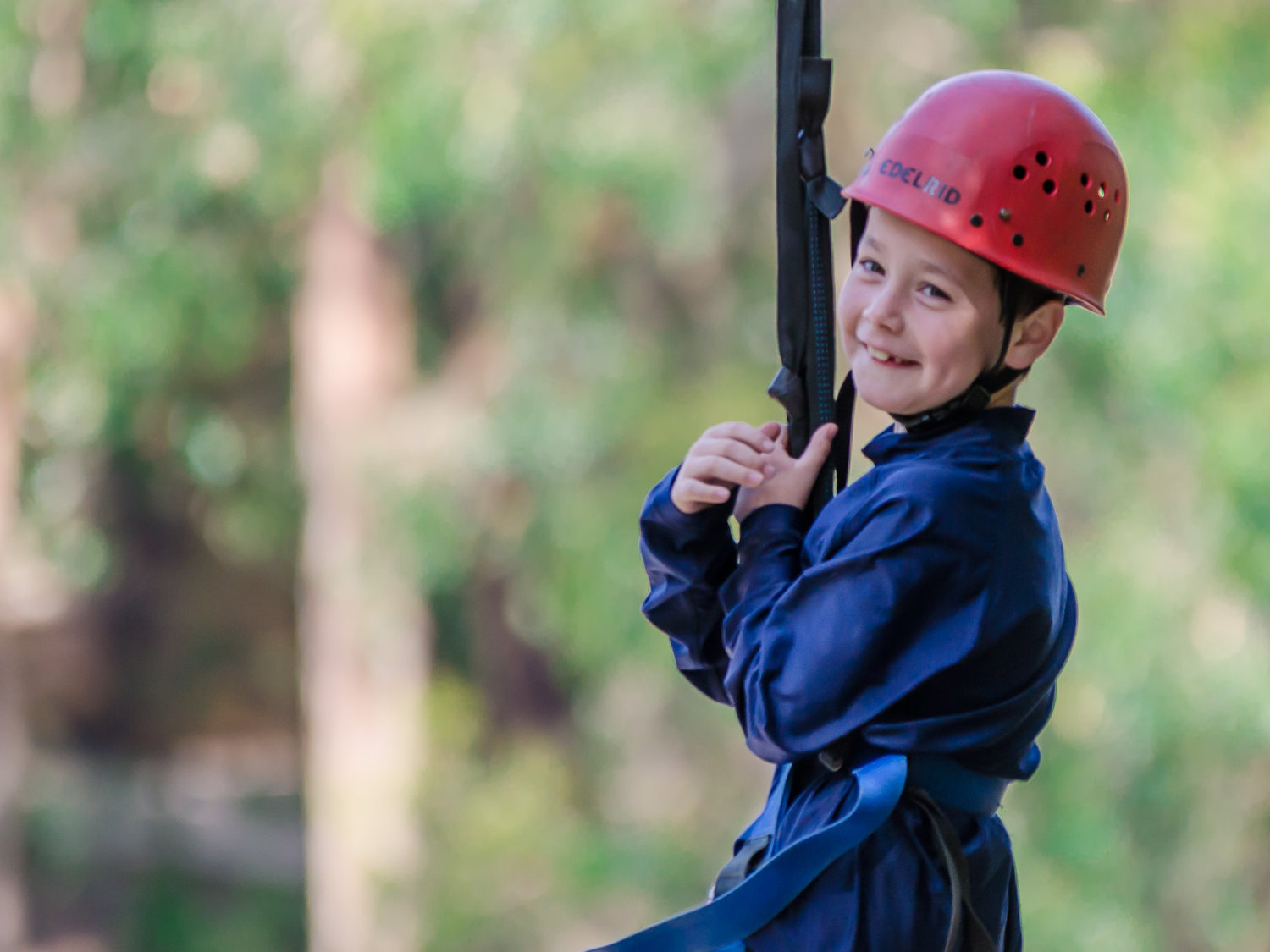A young student wearing a harness and helmet, ready for a high ropes challenge at The Summit adventure camp, Gippsland Victoria