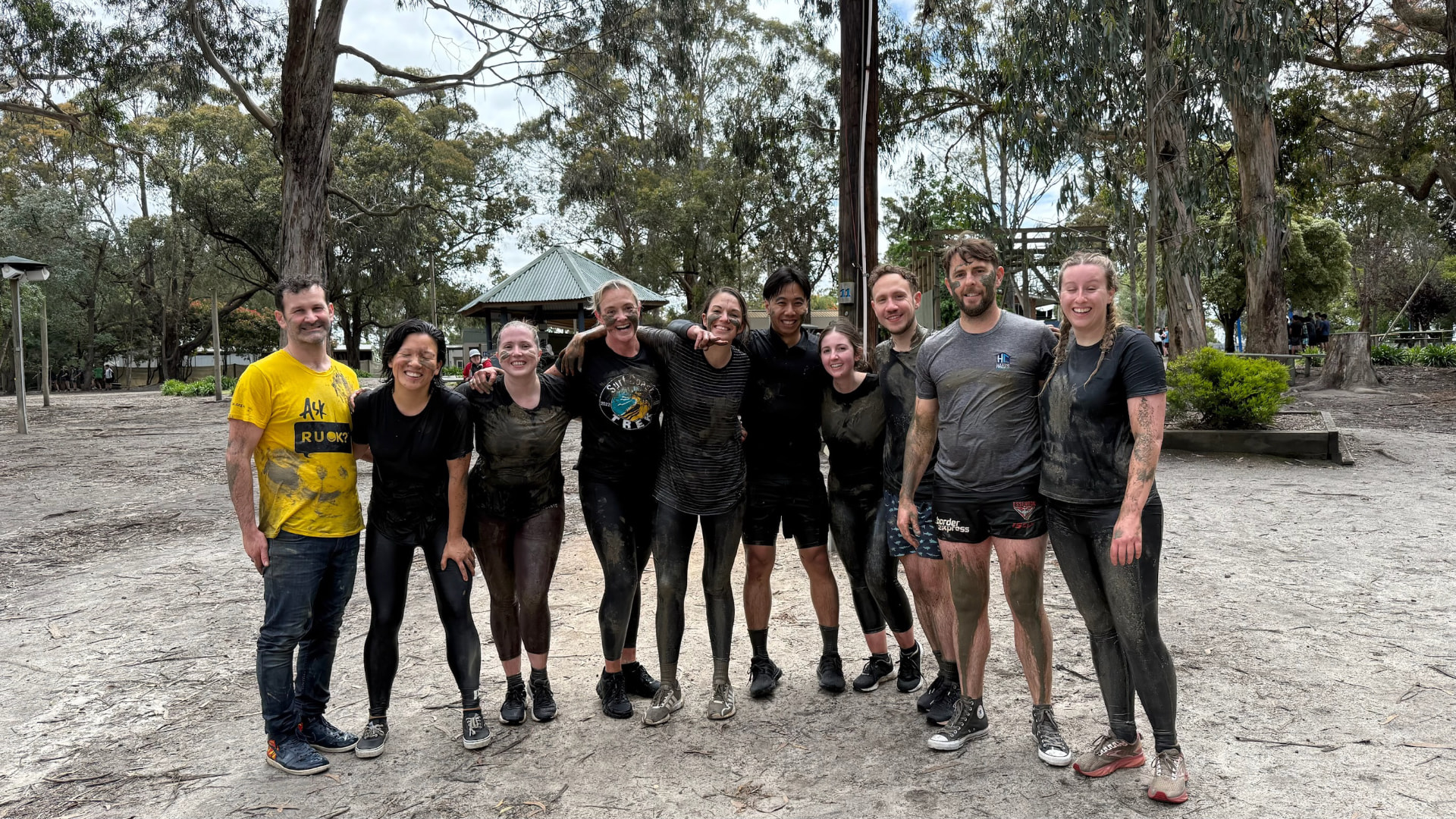 Corporate team covered in mud after an outdoor challenge at The Summit, Gippsland